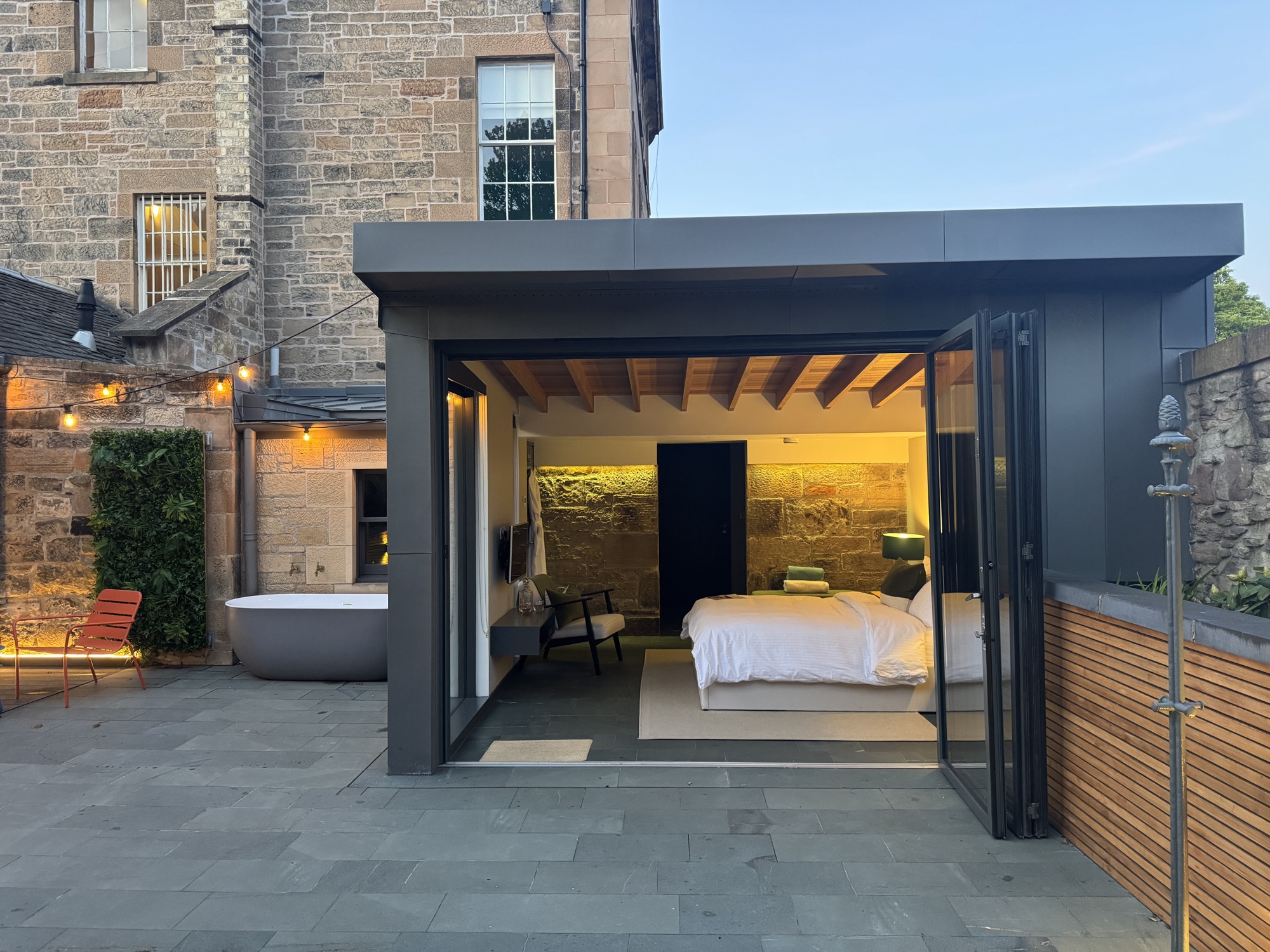 Garden at dusk with bath and bifold doors open wide