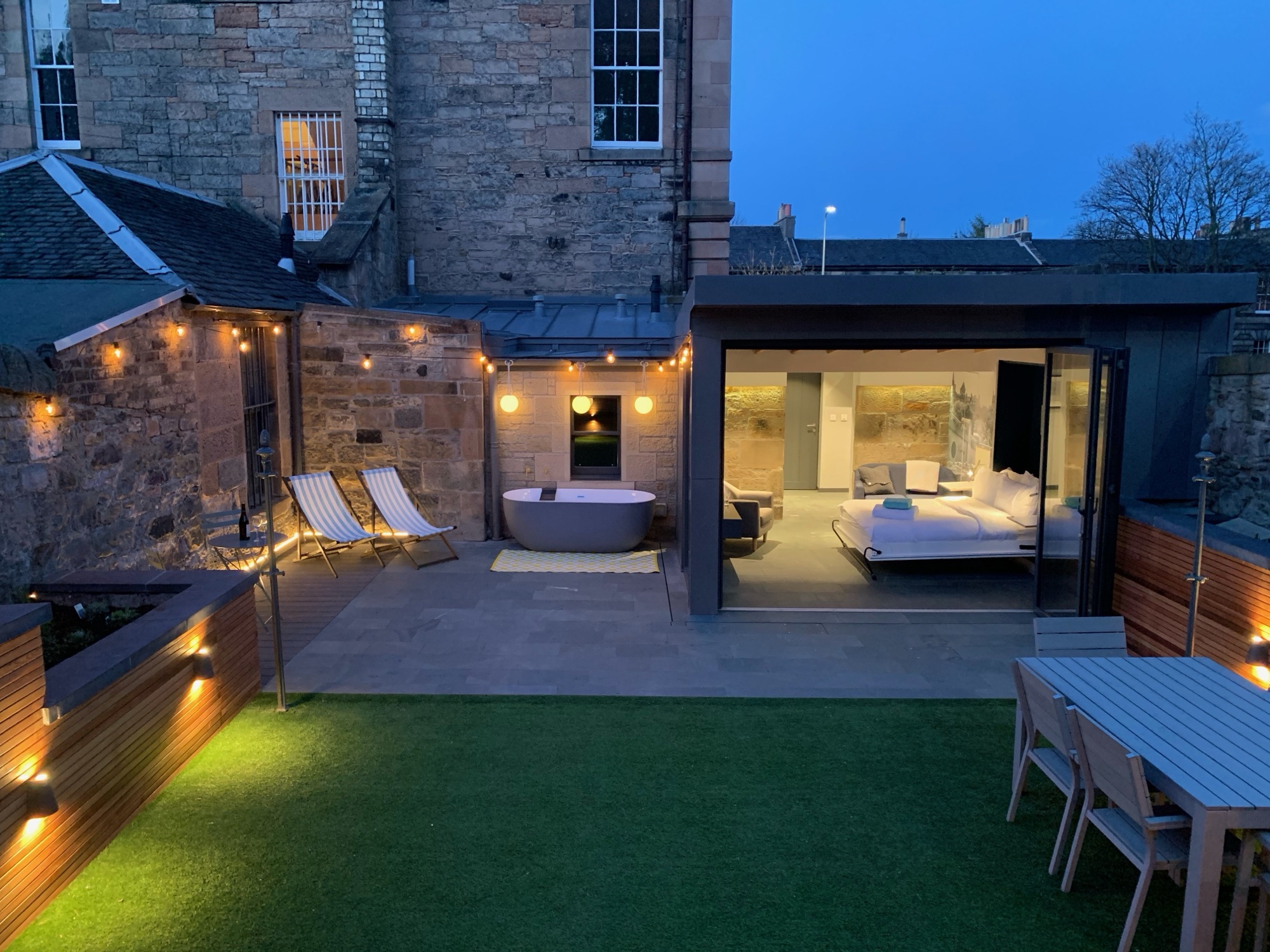Walled garden fully lit at night with outdoor bath