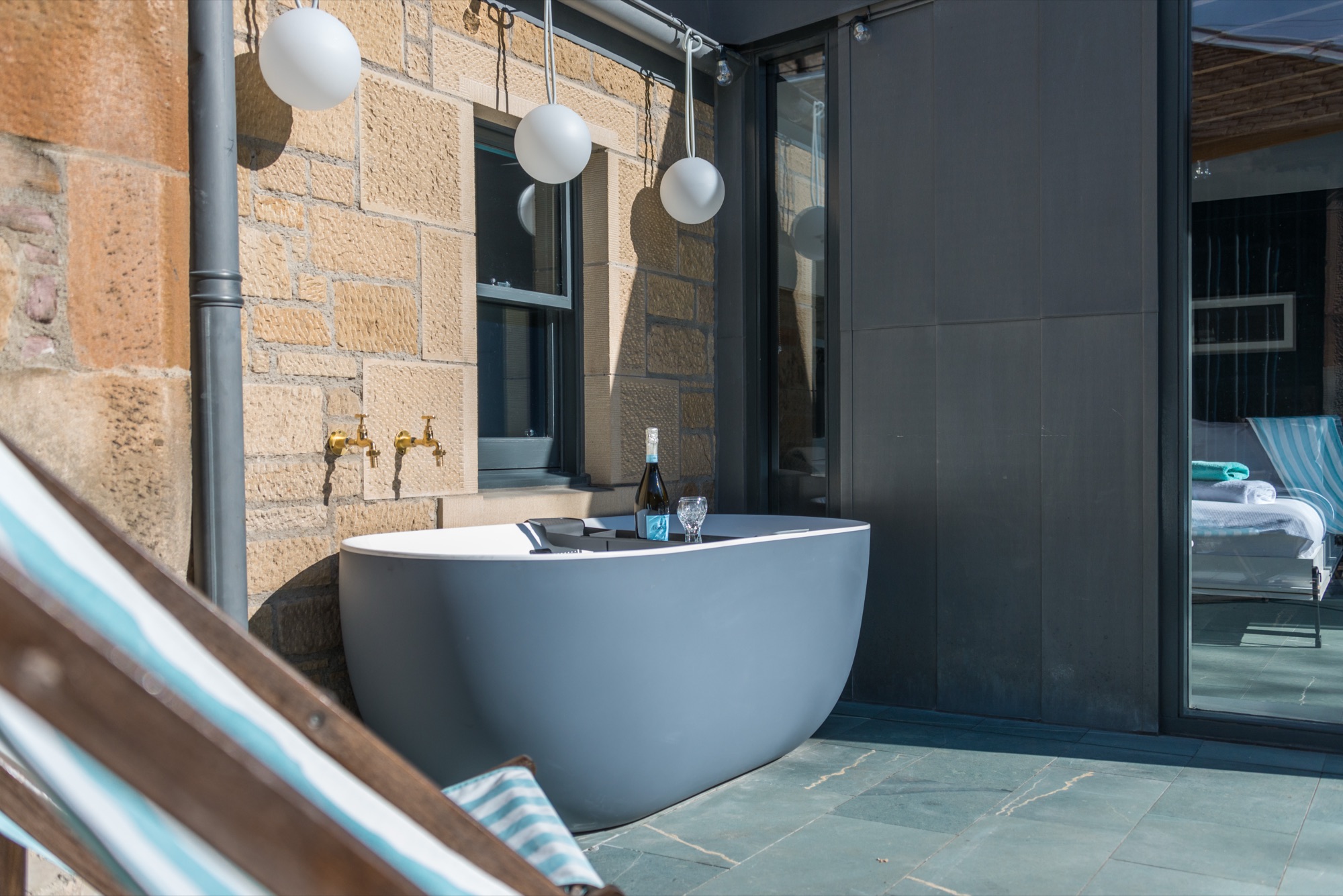 Outdoor bath with champagne and deckchair on terrace